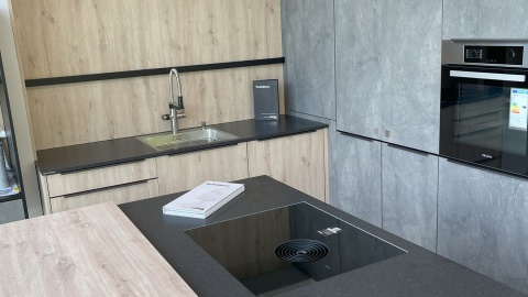 Kuchnia z ciemnym blatem TechniStone Taurus Terazzo Dark i jasną zabudową.