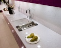 Jasny blat TechniStone Starlight White w kuchni z fioletowymi frontami.