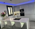 Kuchnia z wyspą TechniStone Starlight White i jasną zabudową na wysoki połysk.