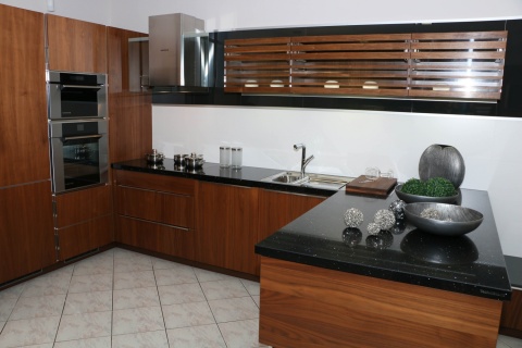 Kuchnia z czarnym blatem TechniStone Starlight Black i ciepłą drewnianą zabudową.