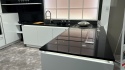Biała kuchnia z dużą wyspą i polerowanym blatem TechniStone Starlight Black.