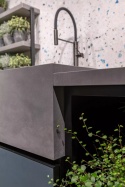 Wyspa kuchenna z FLORIM Stone Cement Dark Grey Matte Soft i czarną baterią.
