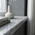 Parapet Bianco Crystal FALCO w jasnym wnętrzu przy oknie, z naturalnym wzorem granitu