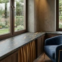 Granitowy parapet Gold Antracite FALCO w eleganckim wnętrzu z drewnem i granatowym fotelem