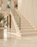 Elegancki hol ze schodami wykończonymi spiekiem FLORIM Stone Gold Travertine w jasnej aranżacji.