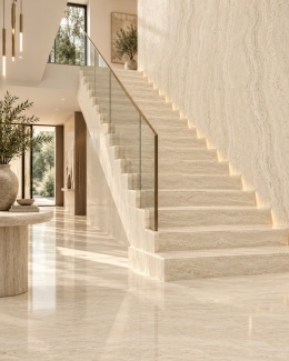 Elegancki hol ze schodami wykończonymi spiekiem FLORIM Stone Gold Travertine w jasnej aranżacji.