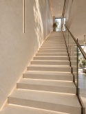 Nowoczesne, długie schody wykończone beżową płytą Sandscape Beige w eleganckim wnętrzu.
