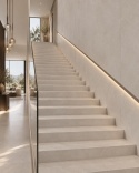 Długie eleganckie schody w minimalistycznym foyer, wykończone jasnoszarym spiekiem Sandscape Grey.