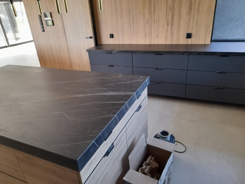 Wyspa kuchenna ze spieku Noir Desir z widocznym użyleniem, elegancka kuchnia z drewnem i czarnymi dodatkami