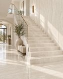 Elegancki hol ze schodami wykończonymi spiekiem FLORIM Stone Pearl Travertine w jasnej aranżacji.