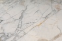 Zbliżenie dolomitu Michelangelo Prime z białym tłem i subtelnymi złotawo-szarymi żyłami.