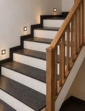 Klasyczne schody z ciemnego granitu Black Pearl i drewnianą balustradą w jasnym, eleganckim wnętrzu.