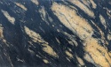 Zbliżenie granitu Etna Natural z czarno-grafitową bazą i nieregularnymi złoto-beżowymi minerałami.