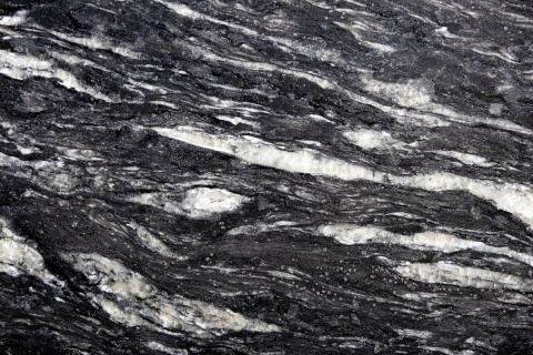 Zbliżenie granitu Cosmic Black szczotkowanego z czarną bazą i szerokimi kremowo-białymi pasmami.