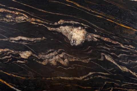 Zbliżenie granitu Cosmic Gold szczotkowanego z czarną powierzchnią i wyrazistymi złotymi żyłami.
