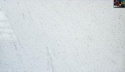 Duża płyta granitu Perfect White poler, białe tło z subtelnymi szarymi smugami i rozsianymi ciemnymi punktami
