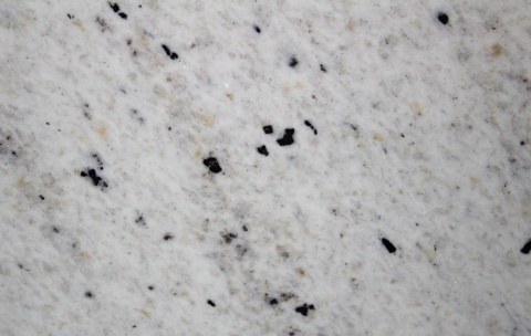 Perfect White poler 20 i 30 mm – zbliżenie białego granitu z drobnymi czarnymi minerałami i delikatnymi szarymi smugami.