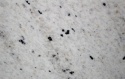 Perfect White poler 20 i 30 mm – zbliżenie białego granitu z drobnymi czarnymi minerałami i delikatnymi szarymi smugami.