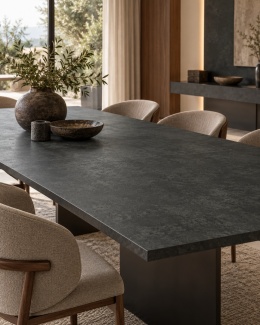 ReSTILE Cemento NERO Natural 20 mm jako stół w eleganckiej jadalni z tapicerowanymi krzesłami.