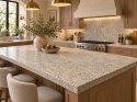 Silvestre Gold Brushed 30 mm – elegancka kuchnia z granitową wyspą, drewnianą zabudową, złotymi dodatkami i jasnymi krzesłami.