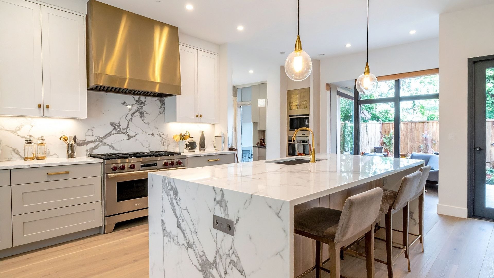 Blat kuchenny z białego spieku kwarcowego z szarym użyleniem, nowoczesna kuchnia z wyspą i złotymi dodatkami.