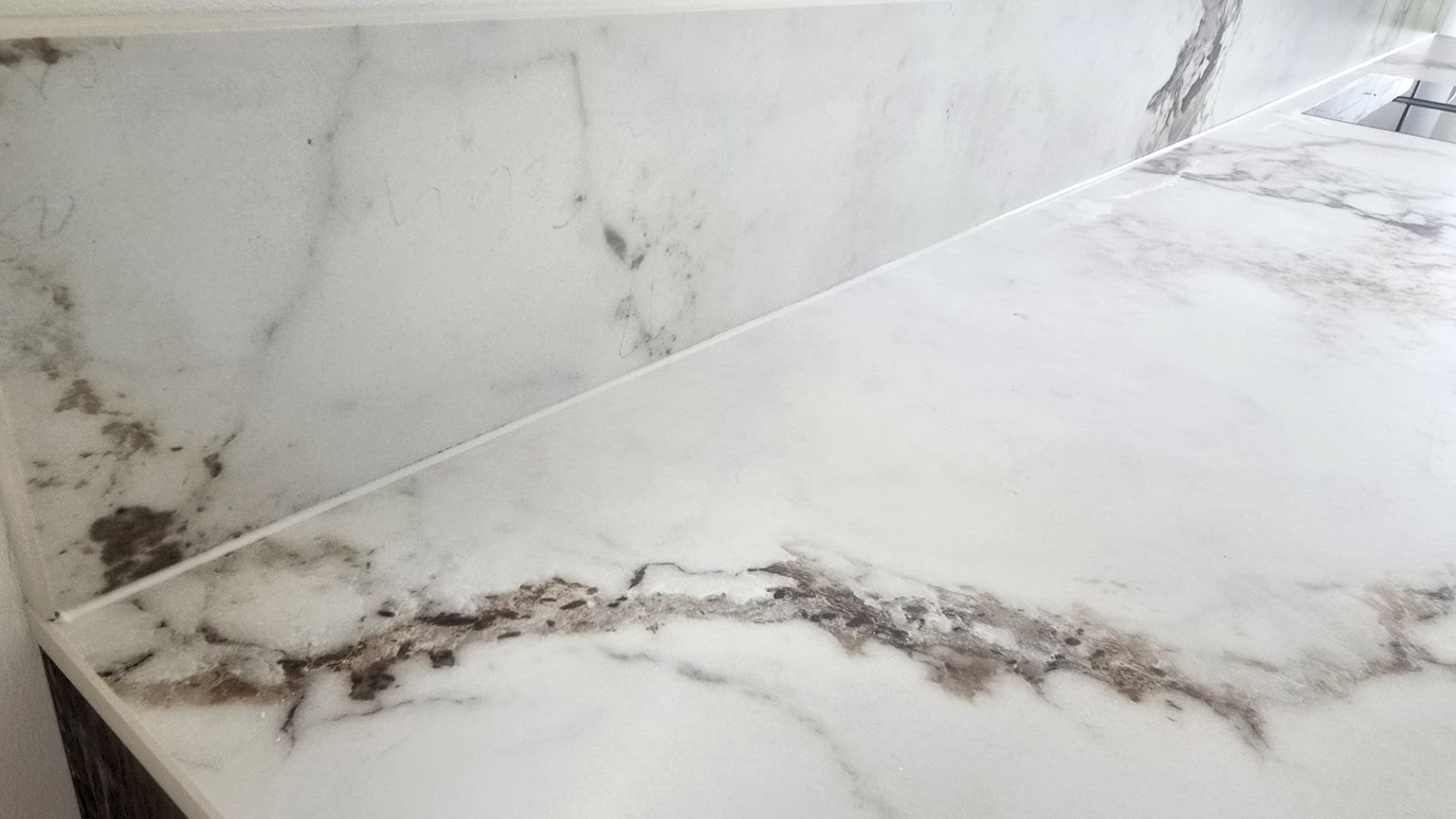 Zbliżenie na linię styku blatu i ściany w kuchni. Spiek kwarcowy Marble Capraia z wyrazistym, naturalnym użyleniem i satynowym wykończeniem powierzchni