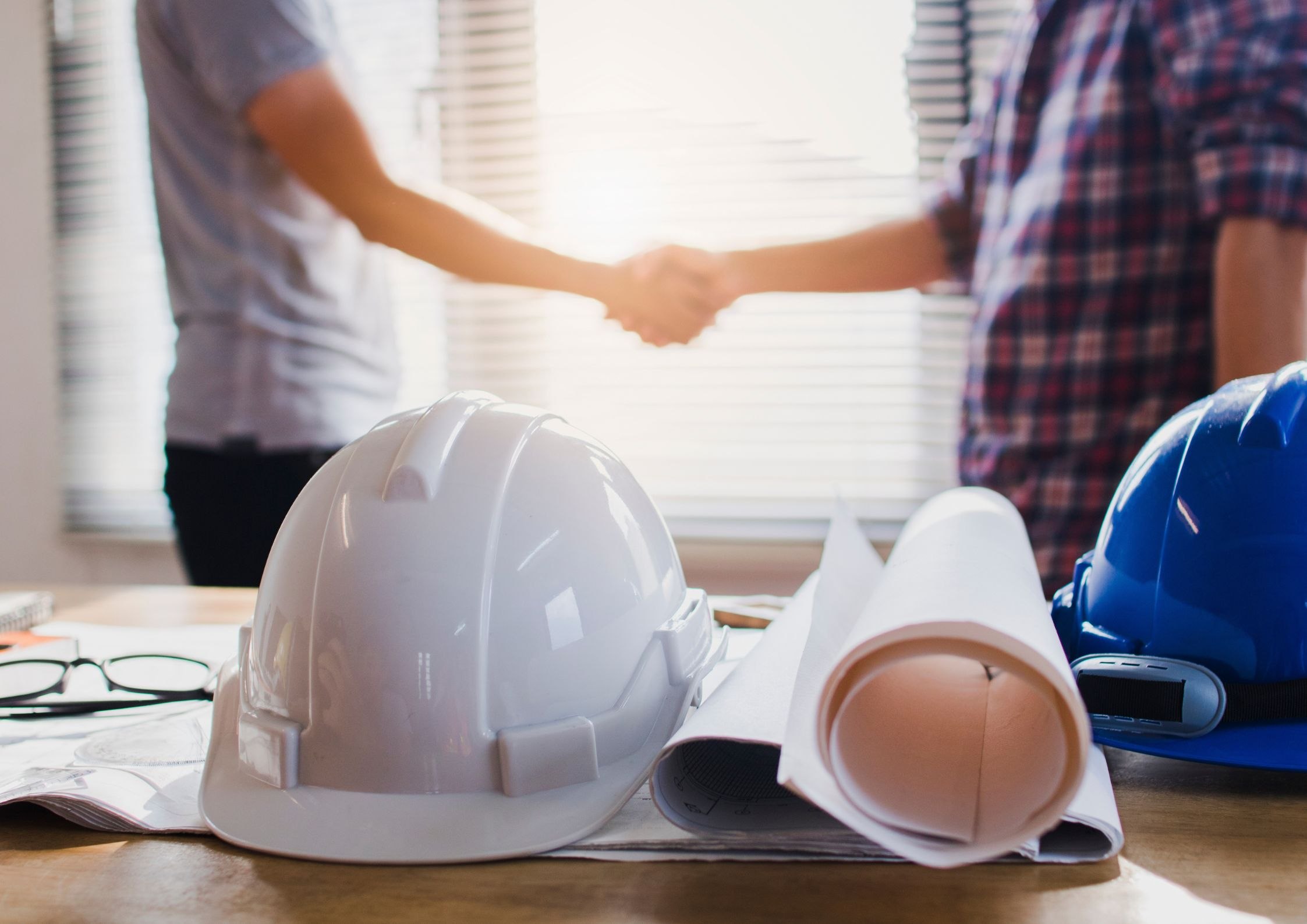 Uścisk dłoni dwóch mężczyzn nad planami