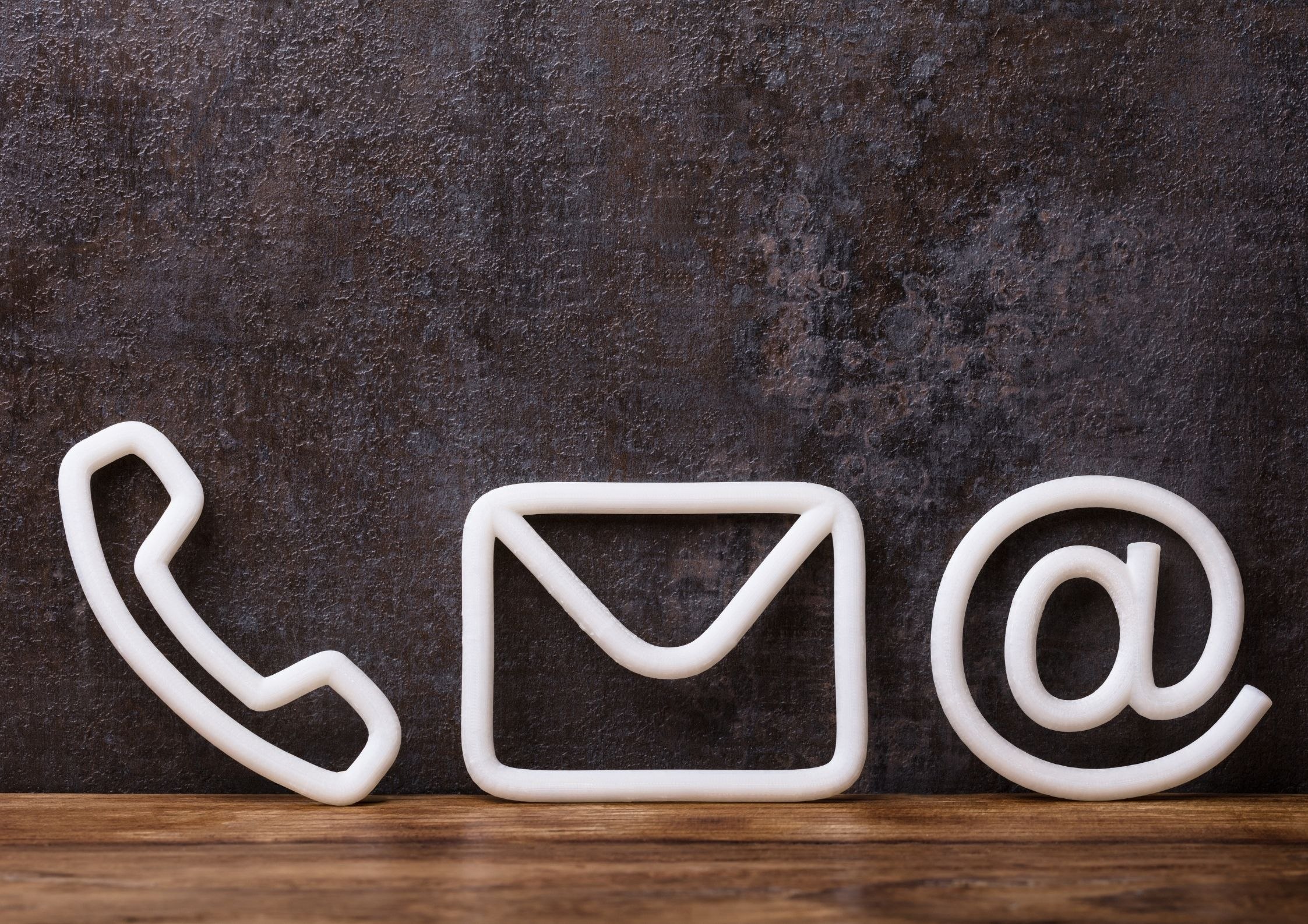 Symbole kontaktu – telefon, e-mail i adres internetowy na ciemnym tle